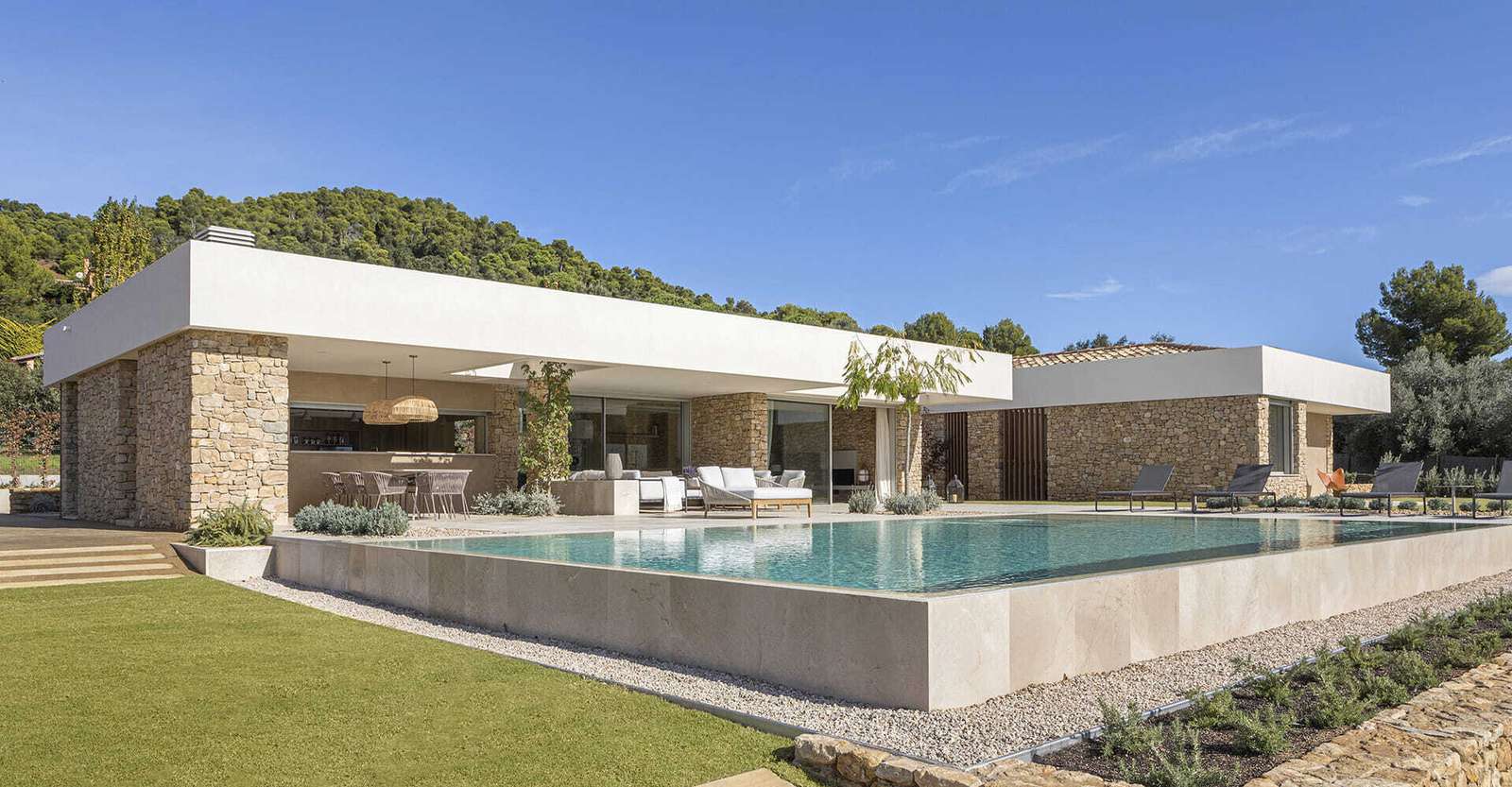 A modern house with stone walls that are highlighted by the use of both exterior and hidden lighting.