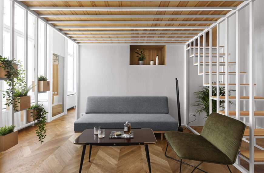 A calm living space with built in wood storage, indoor plants, and doors opening to a small balcony in the heart of Budapest.