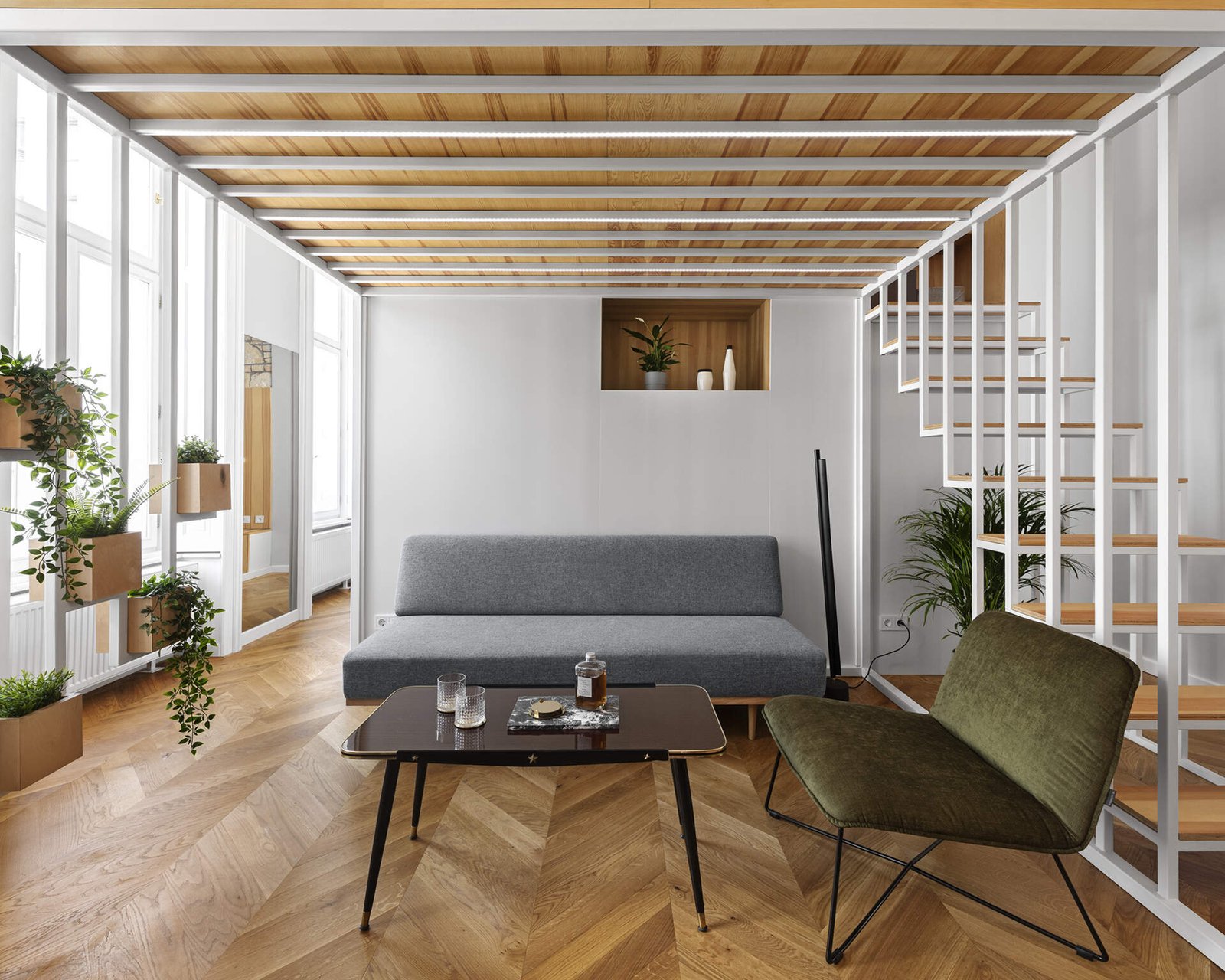 A calm living space with built in wood storage, indoor plants, and doors opening to a small balcony in the heart of Budapest.