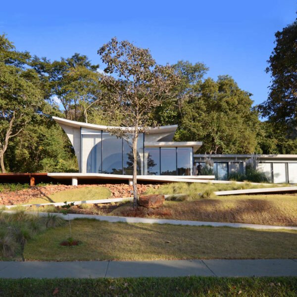 A winding concrete ramp leads up to Casa Joy in Brazil, revealing a sculptural modern home defined by six dramatic concrete arches and a concave roof overlooking the valley.