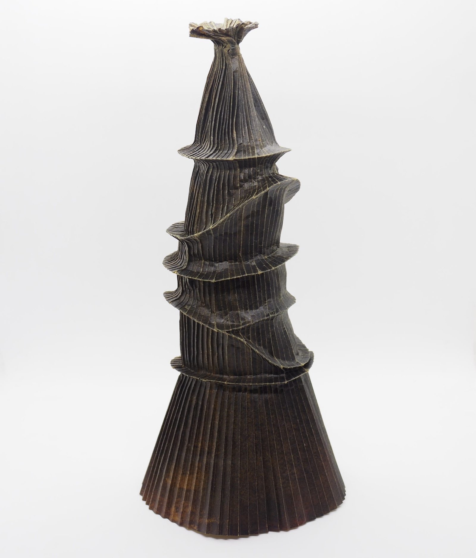 An origami paper vase with a wide base and narrow top, with uneven rim details around the body