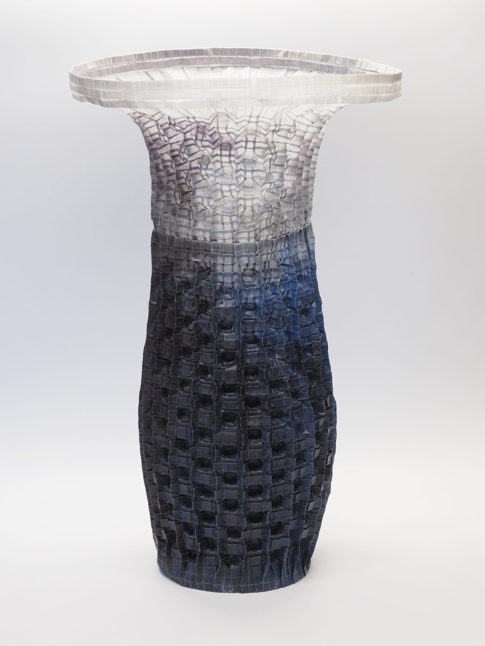 An origami paper vase with a wide lip on top and a white-to-indigo gradient