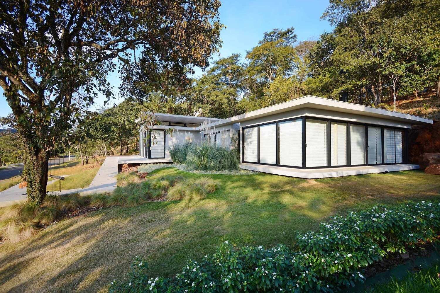 A winding concrete ramp leads up to Casa Joy in Brazil, revealing a sculptural modern home defined by six dramatic concrete arches and a concave roof overlooking the valley.