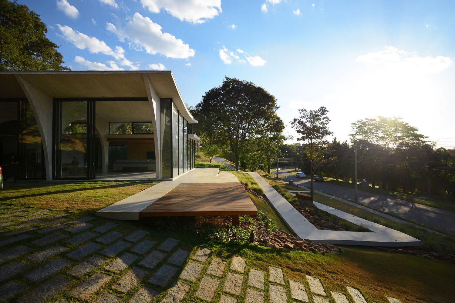 A winding concrete ramp leads up to Casa Joy in Brazil, revealing a sculptural modern home defined by six dramatic concrete arches and a concave roof overlooking the valley.