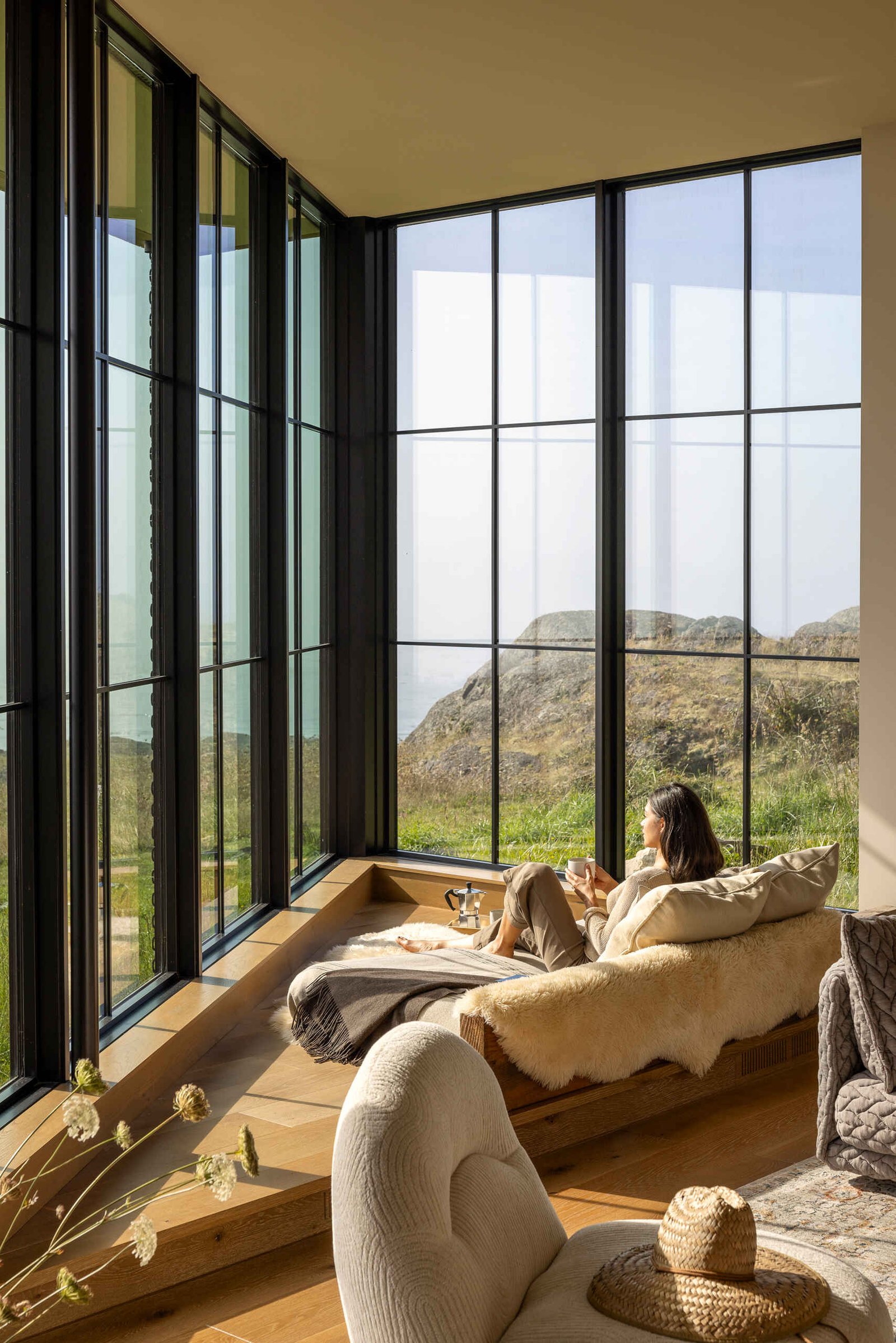 Neutral interiors and large glass doors frame uninterrupted views of water and rock.