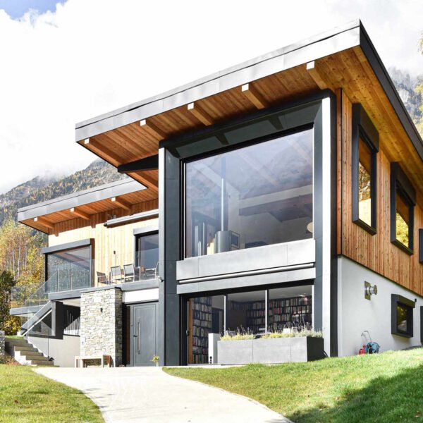 This Chamonix renovation features a massive black framed picture window that perfectly captures mountain views while flooding the home with natural light.