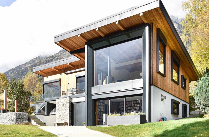 This Chamonix renovation features a massive black framed picture window that perfectly captures mountain views while flooding the home with natural light.