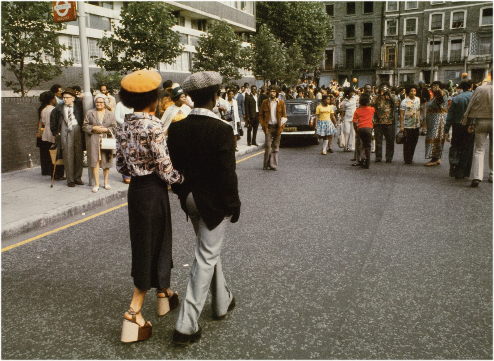 a photo of a stylish couple walking along a street with their backs to the photographer