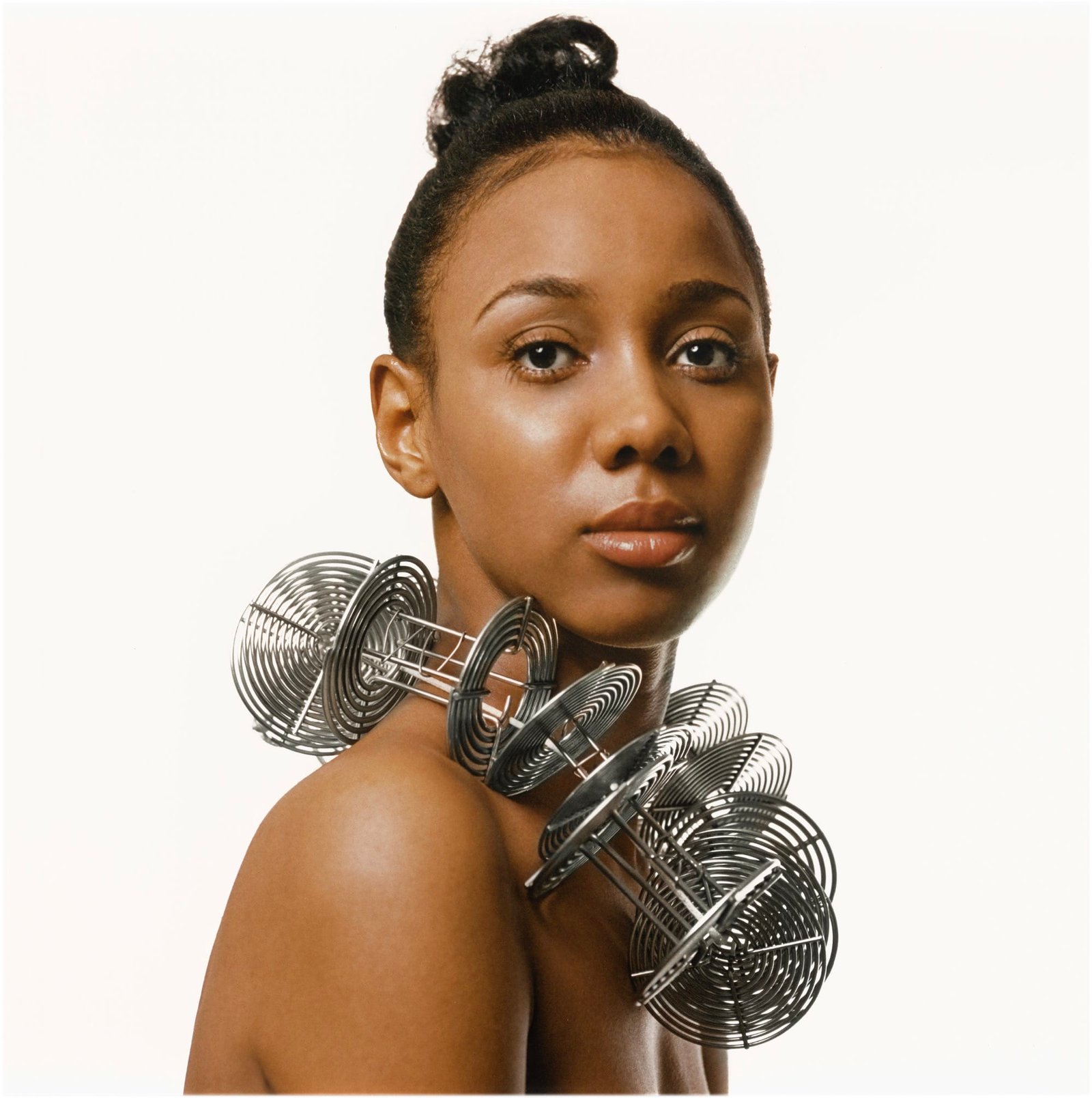 a portrait of a young Black woman with a sculptural silver necklace