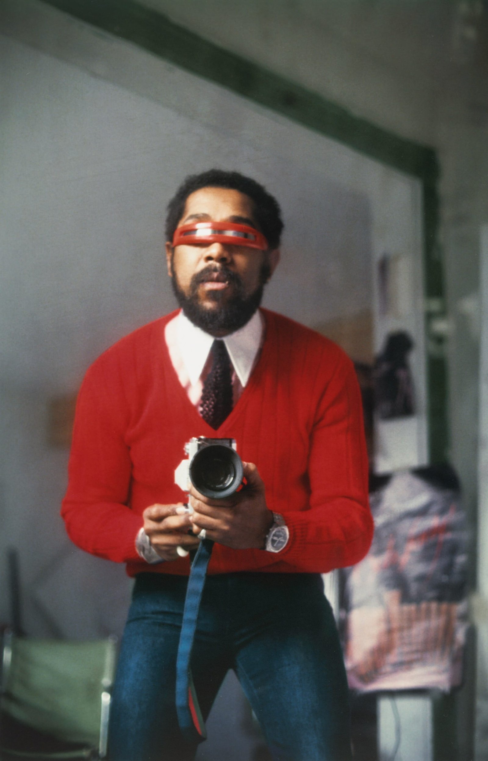 a photo of a photographer capturing himself in a mirror while wearing a red sweater