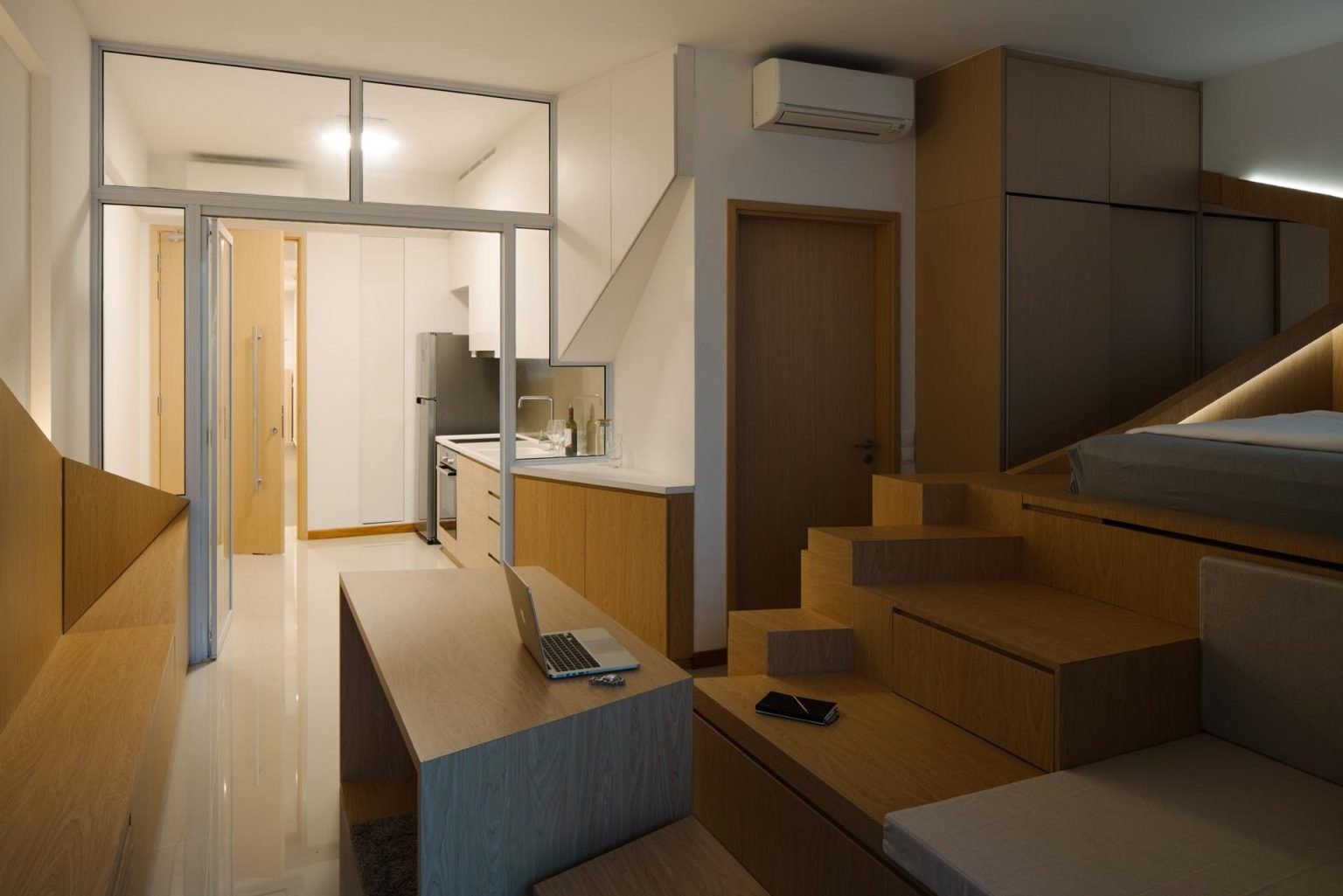 A glass partition wall helps organize this small Singapore apartment while keeping the interior bright, open, and filled with natural light.