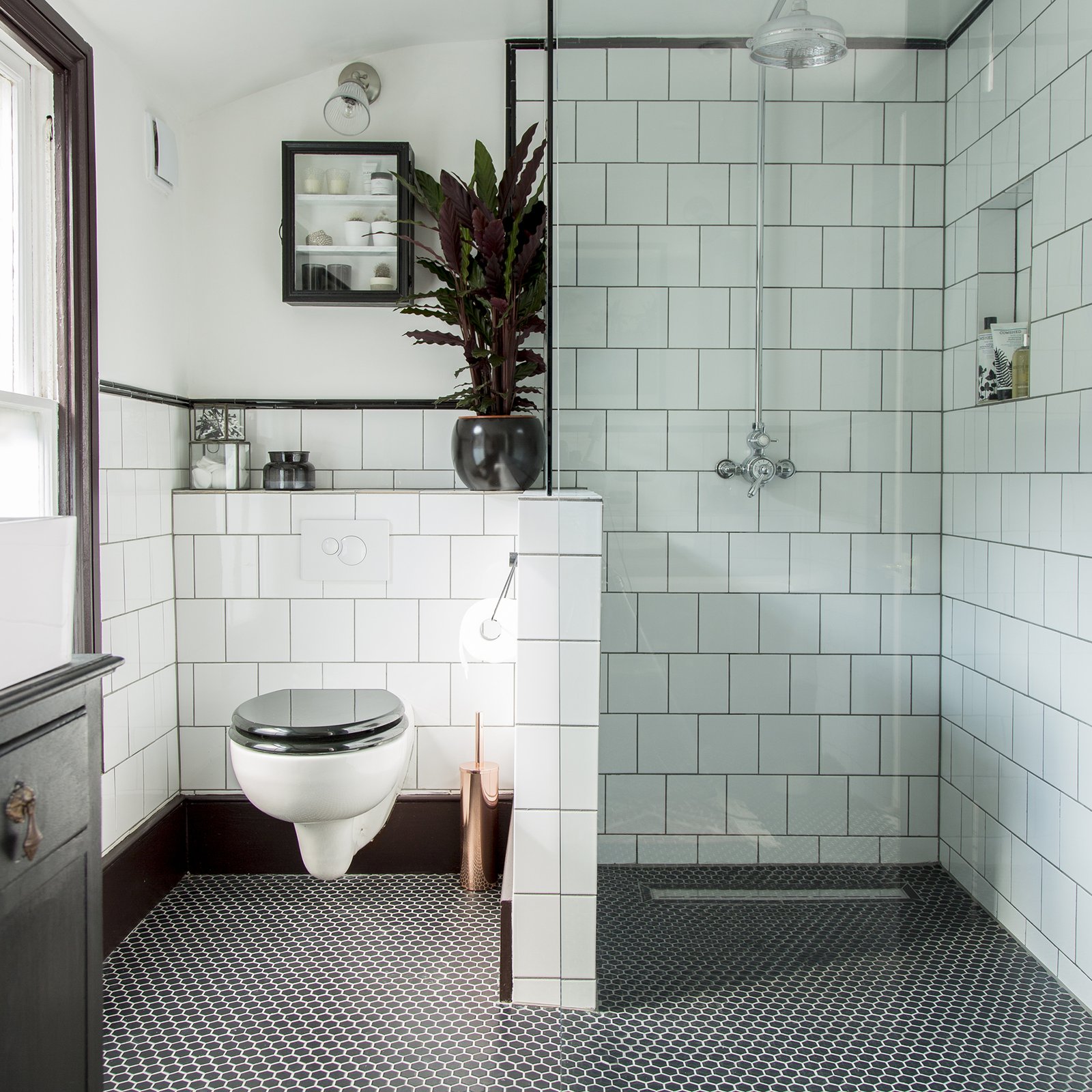 black and white bathroom with white wall tiles and black mosaic flooring