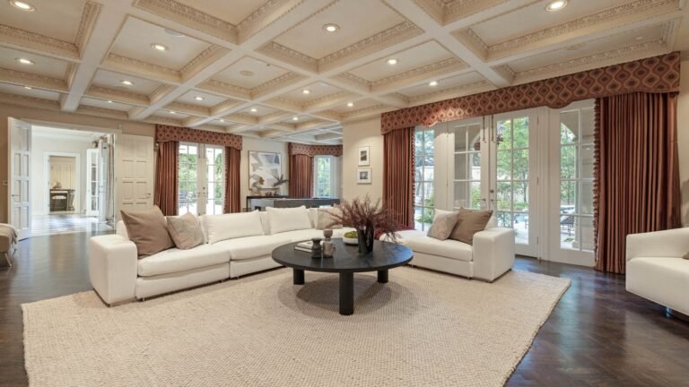 Living area with white sofa round black table beige area rug french doors