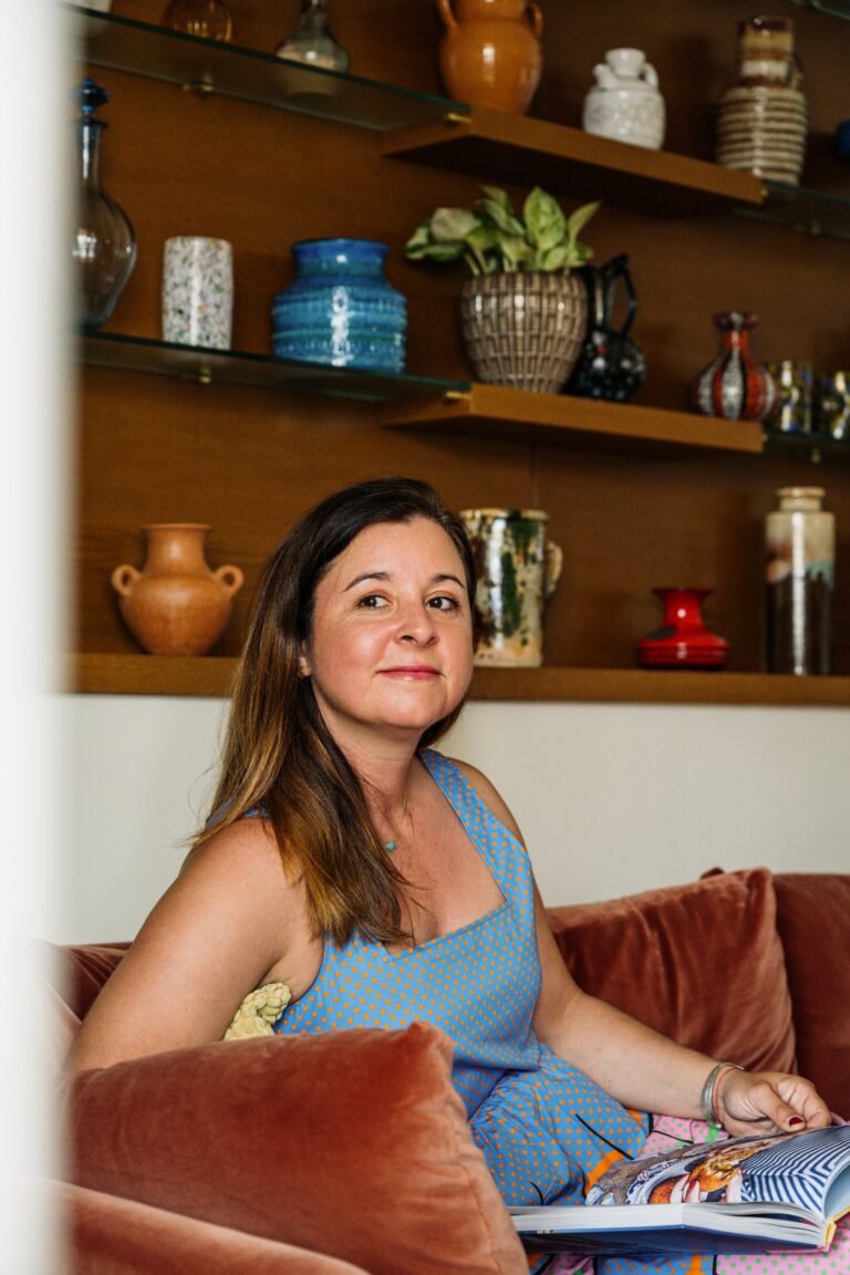 Katie lounges on her sofa with her collection of vessels in the background.