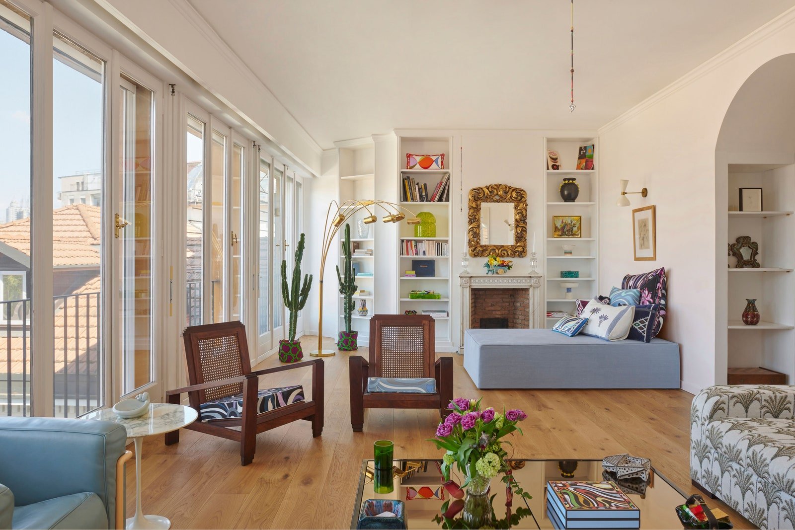 living area with white walls and builtin bookshelves boxy blue daybed brick fireplace coffee table and seating in foreground