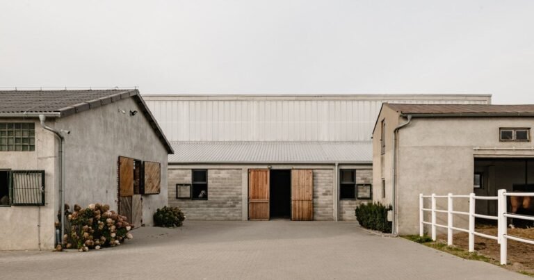 raw concrete, steel panels, and wood wrap wiercinski studio’s equestrian center in poland