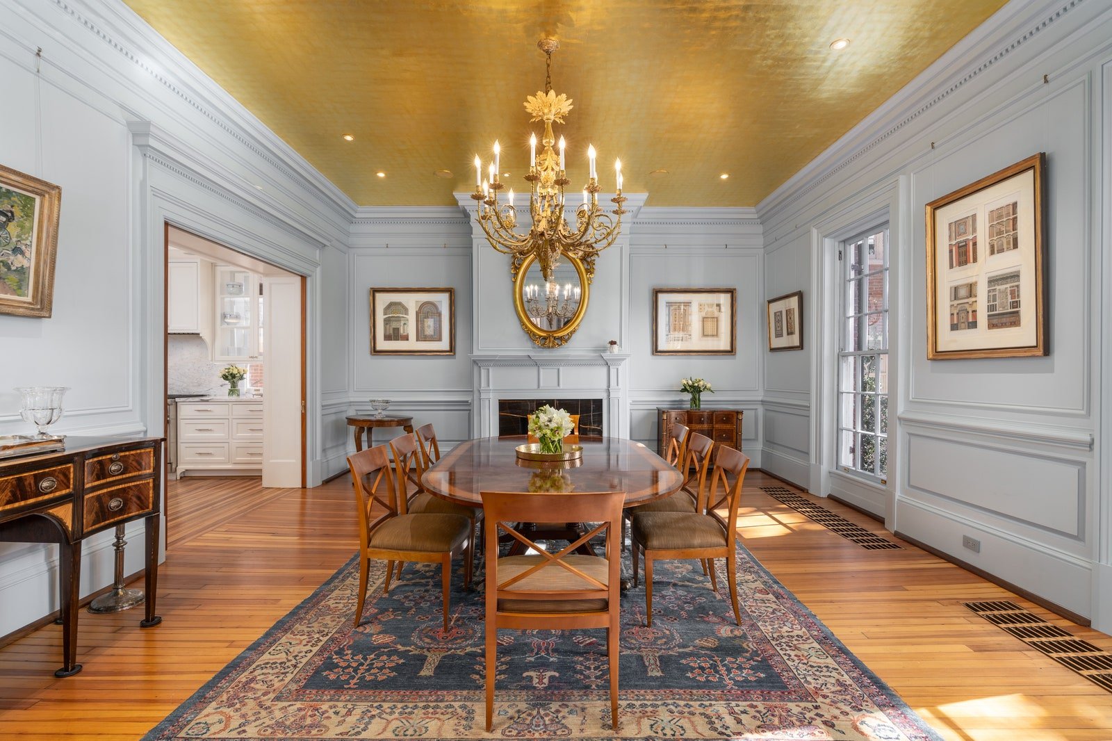 A dining room with traditional furniture light blue walls and gold painted ceiling