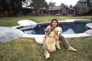 Patrick Swayze with dog near swimming pool outside ranch home