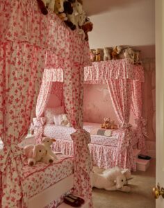 Two pink canopy beds lined with stuffed animals