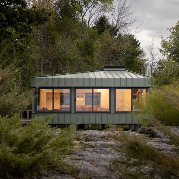 A modern cabin clad in sage green standing seam metal siding.