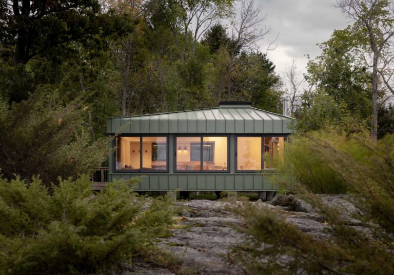 A modern cabin clad in sage green standing seam metal siding.