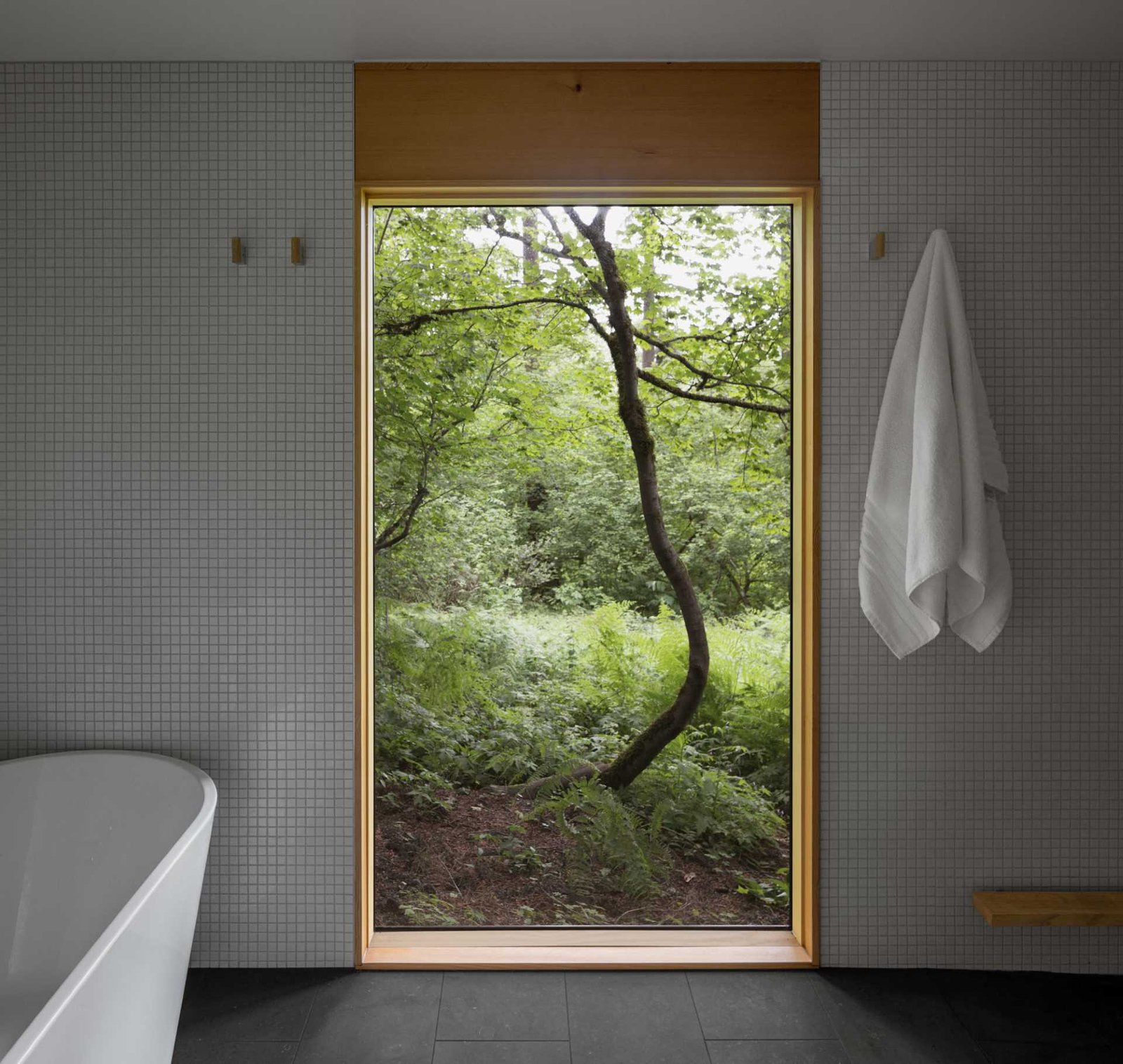 A modern bathroom with a freestanding soaking bathtub and a large window.