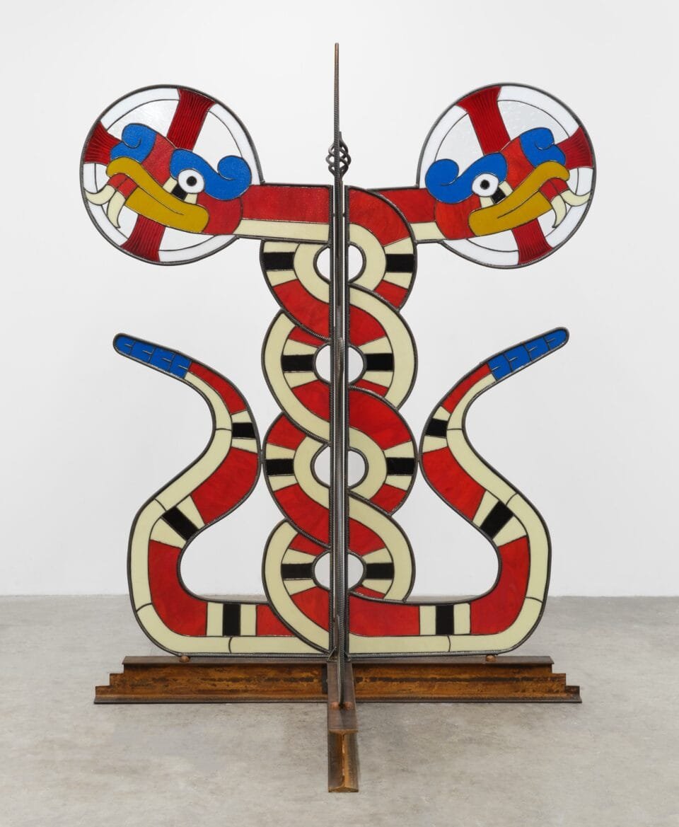 a freestanding sculpture of two intertwined red-and-yellow snakes