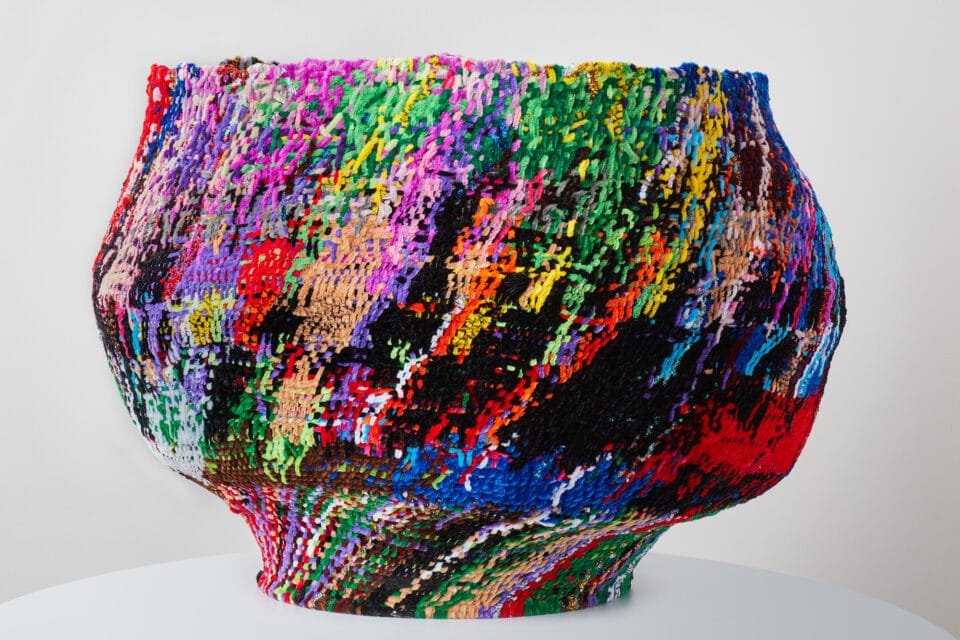 a vase made from woven pipe cleaners in colorful shades
