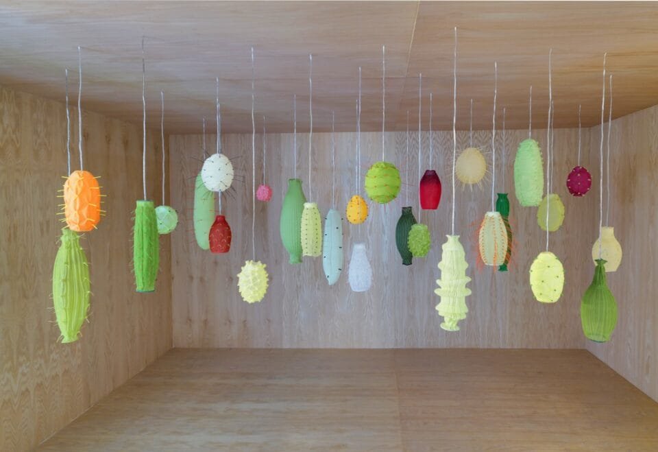 a room with numerous illuminated suspended lights, all loosely reminiscent of tropical fruits
