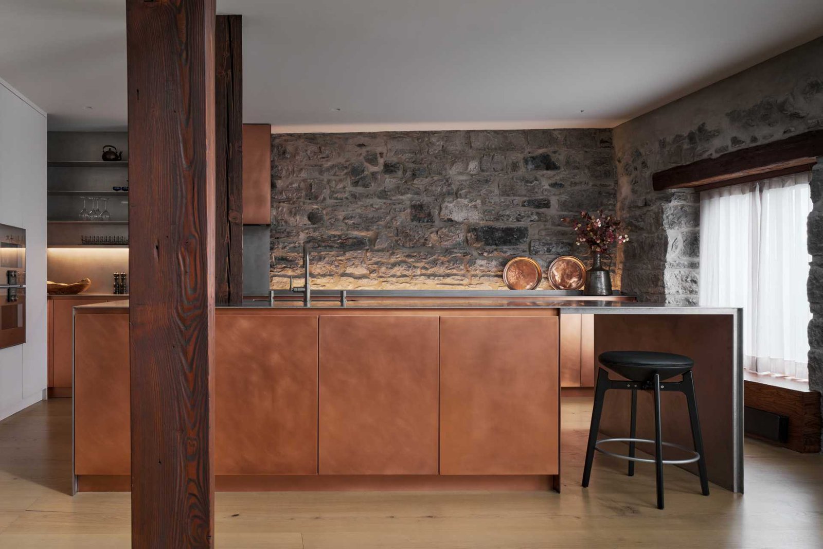 This modern kitchen in a renovated historic loft, features striking copper cabinetry and a stainless steel countertop.