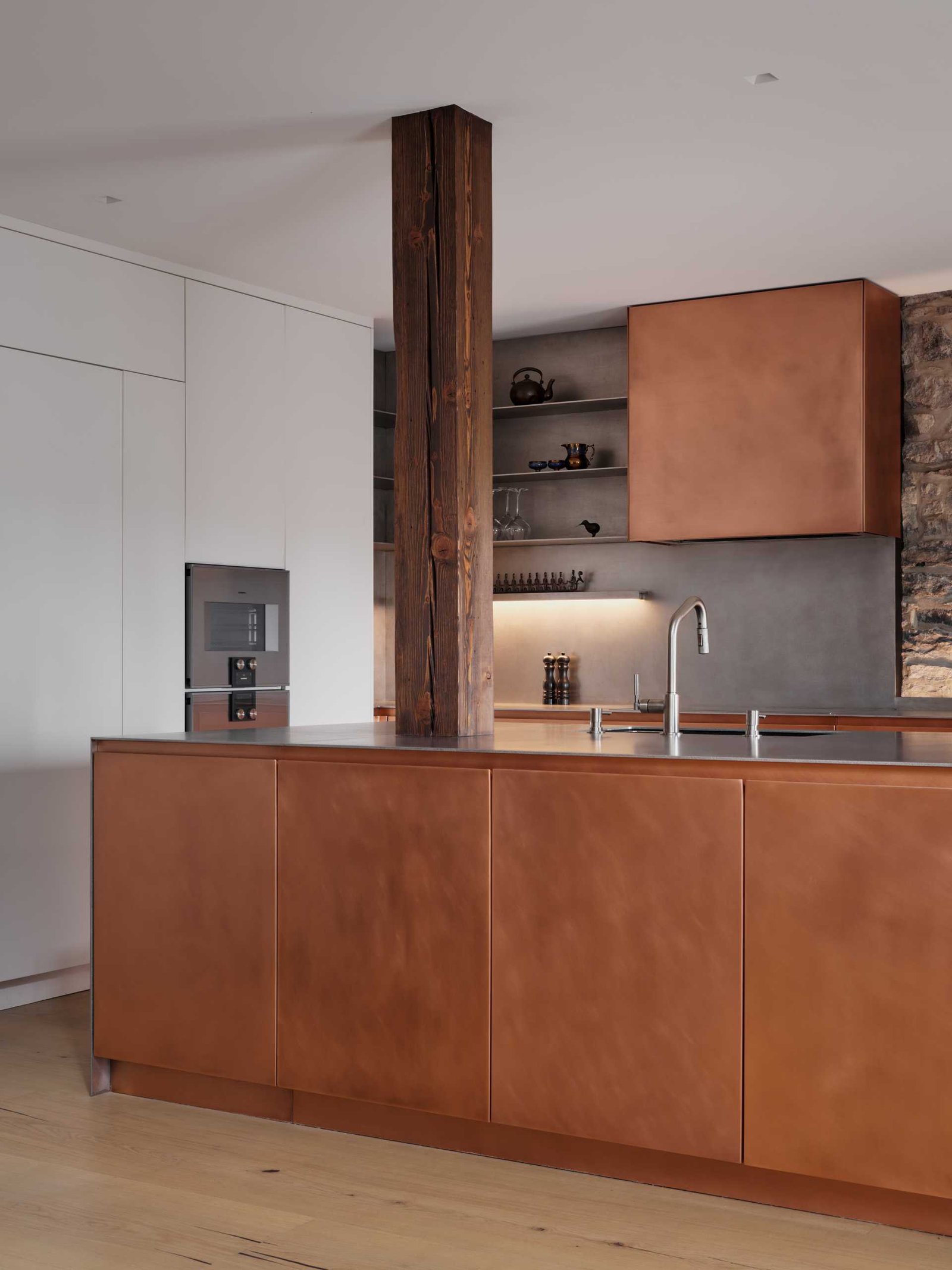 This modern kitchen in a renovated historic loft, features striking copper cabinetry and a stainless steel countertop.