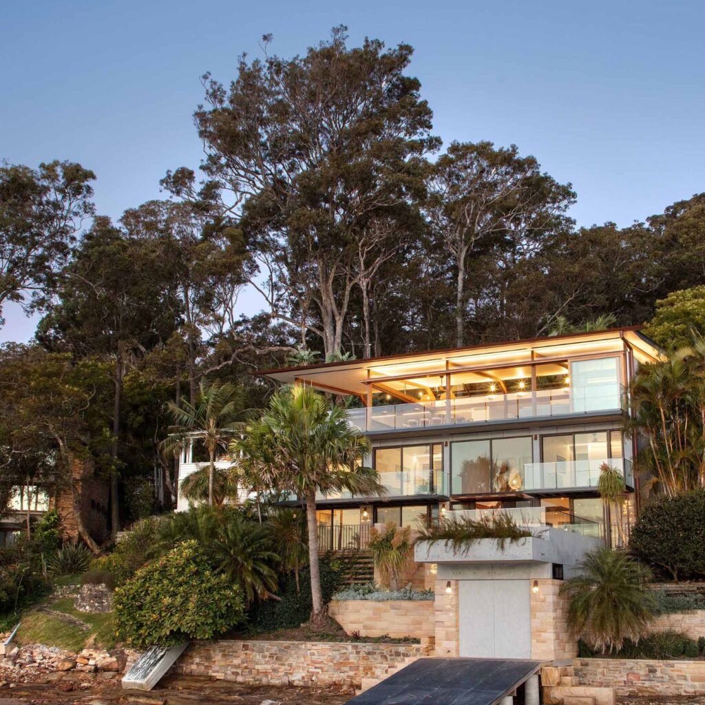 A modern waterfront home features a lightweight floating roof and timber stacking doors that slide away to open the living areas completely to the external terraces and verandah.
