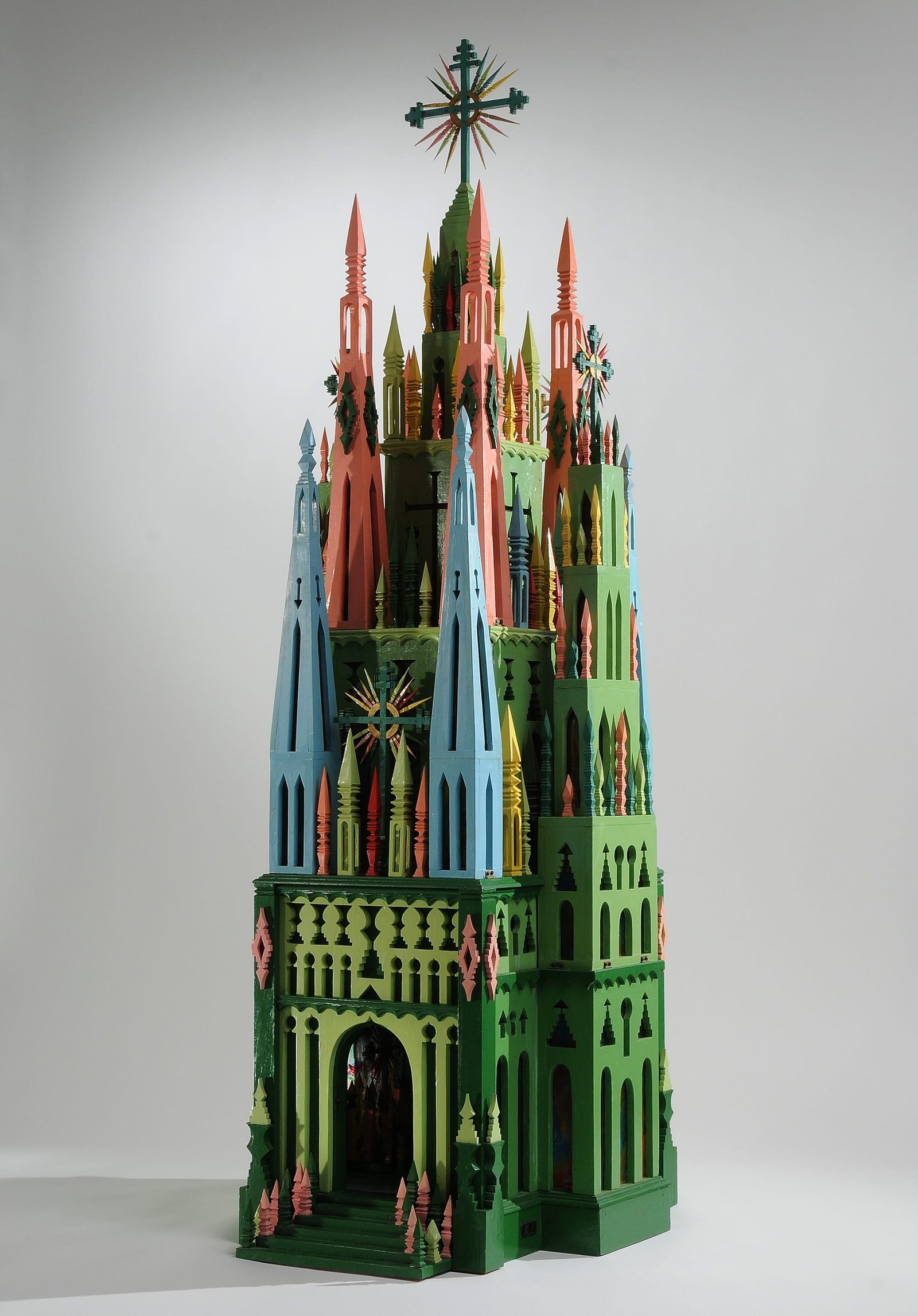 an elaborate wood carved cathedral in green, pink, and blue