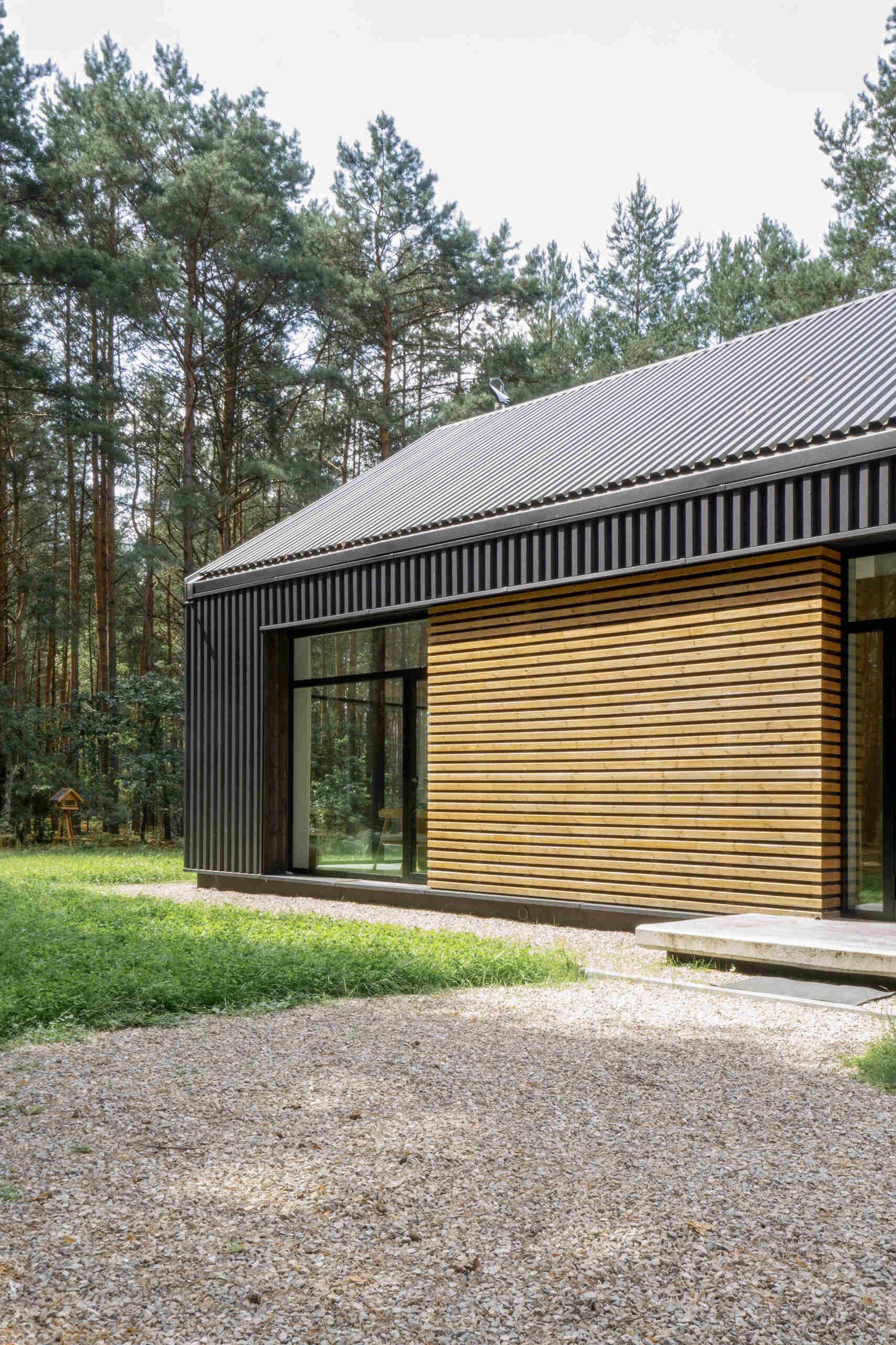 The facade of this modern home is clad in black metal, creating a striking and contemporary appearance, while wood accents add warmth and a natural touch to the exterior.