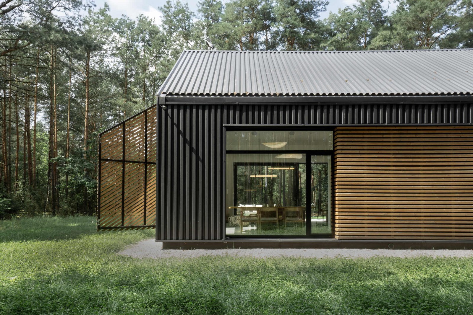 The facade of this modern home is clad in black metal, creating a striking and contemporary appearance, while wood accents add warmth and a natural touch to the exterior.
