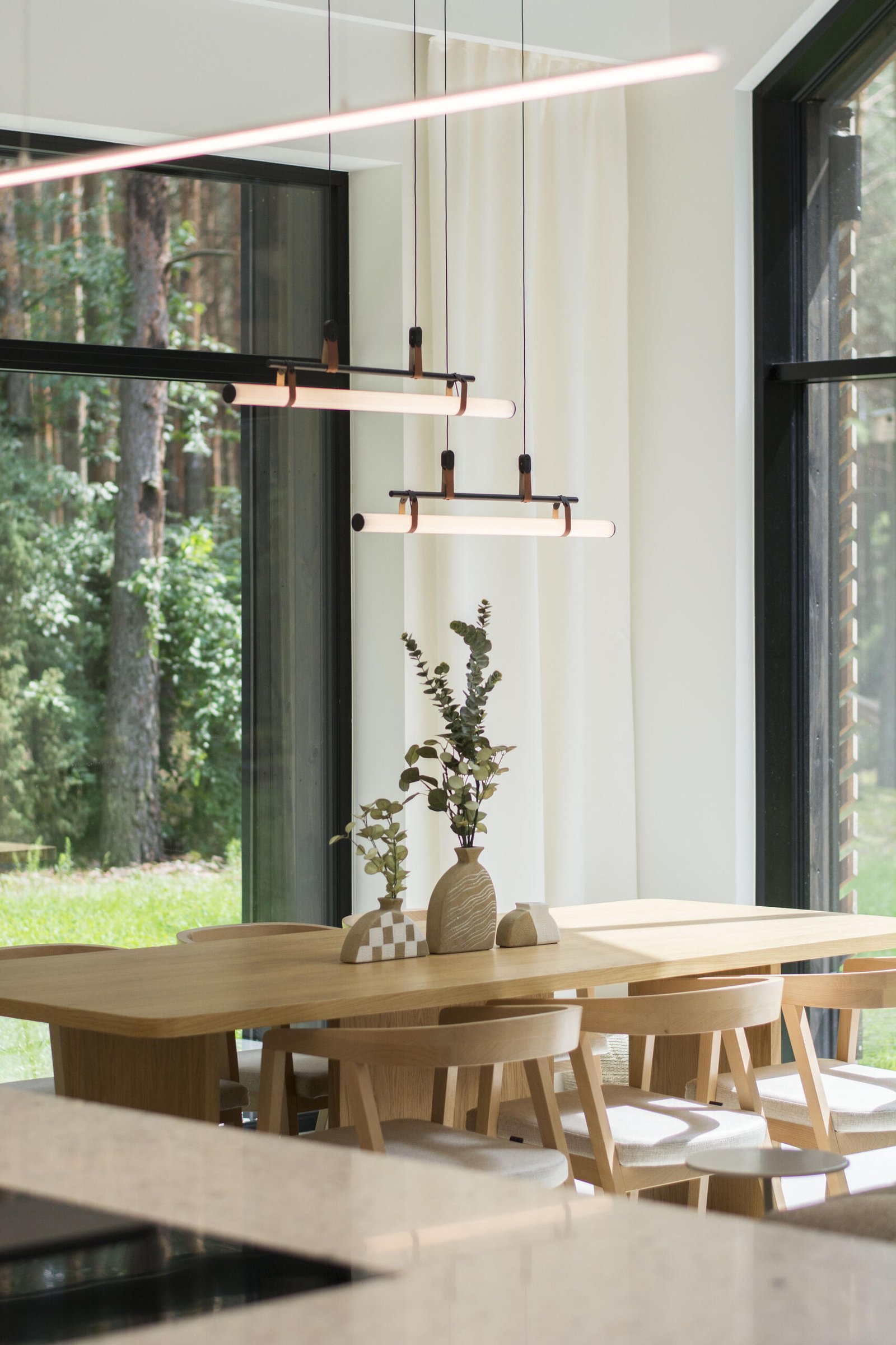 Throughout this modern home, like in the dining area, natural materials such as wood and concrete have been used extensively, adding a sense of warmth and grounding to the sleek design.