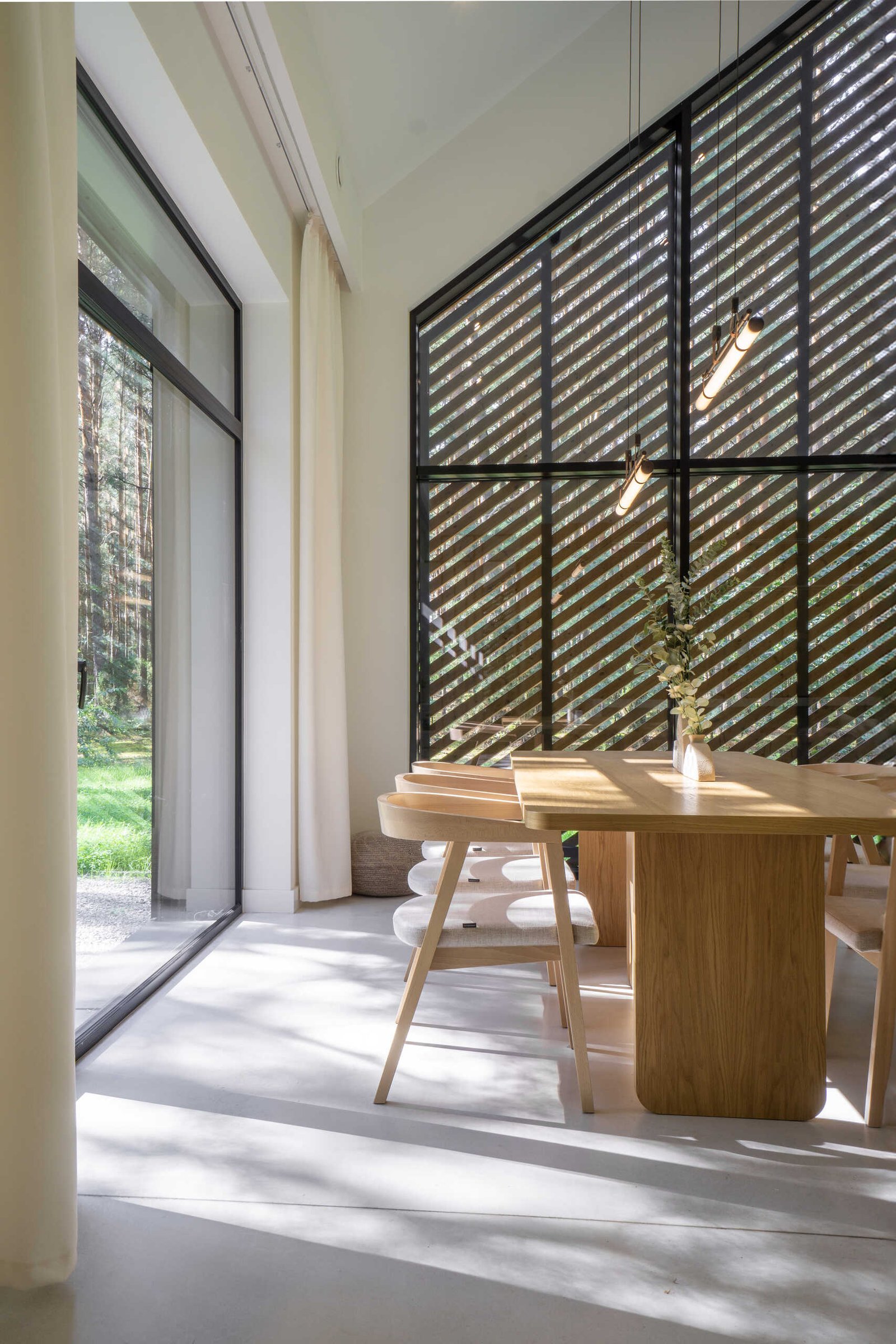 Throughout this modern home, like in the dining area, natural materials such as wood and concrete have been used extensively, adding a sense of warmth and grounding to the sleek design.