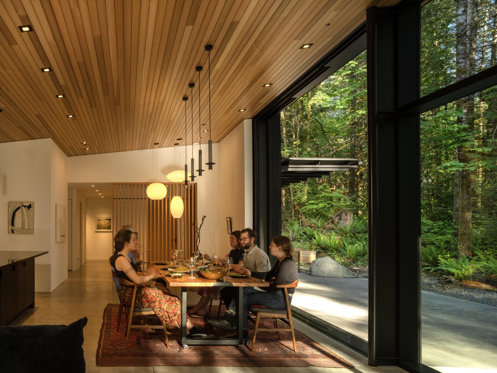  Indoor-outdoor dining made effortless. The patio and dining area open directly to the forest, with a shared material palette that connects meals to nature.
