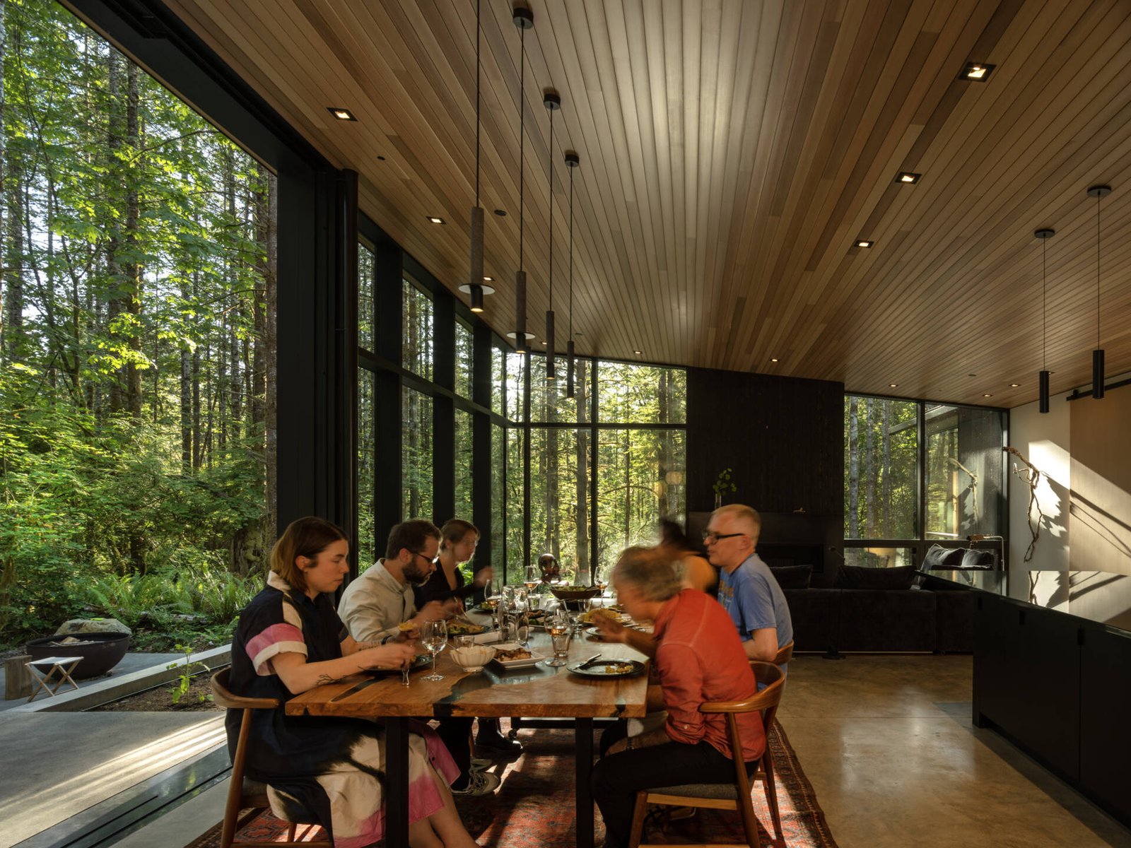  Indoor-outdoor dining made effortless. The patio and dining area open directly to the forest, with a shared material palette that connects meals to nature.