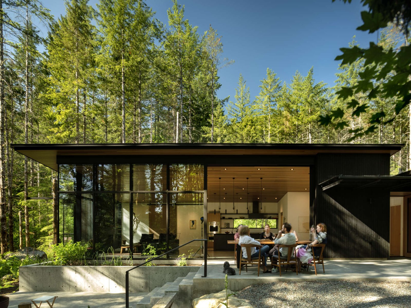  Indoor-outdoor dining made effortless. The patio and dining area open directly to the forest, with a shared material palette that connects meals to nature.