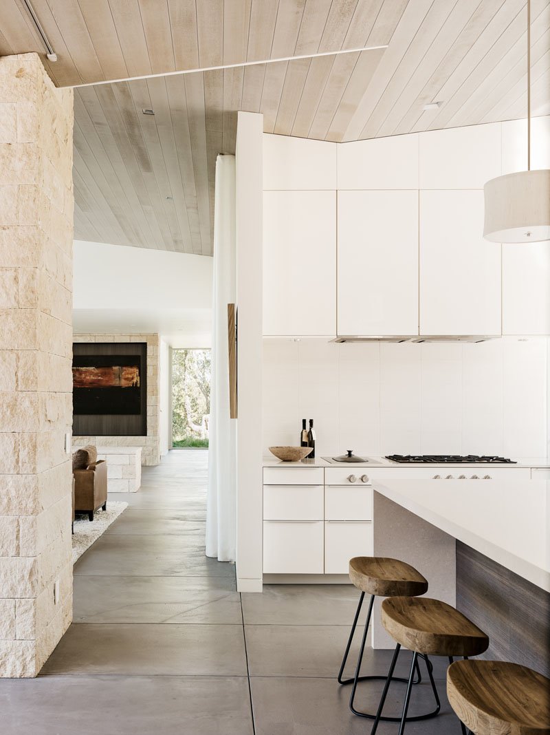 A chef’s dream kitchen with white cabinetry, a spacious island, and windows framing views of the central courtyard and oak tree.