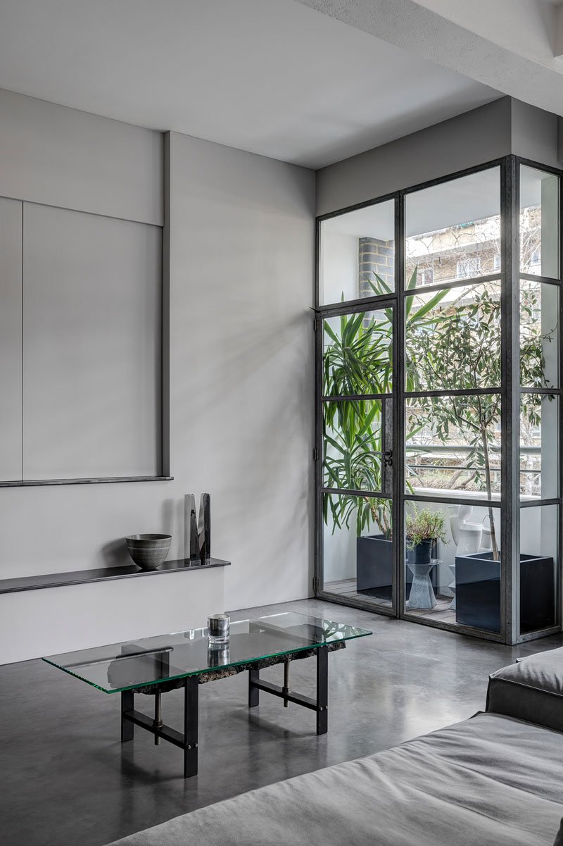 A small balcony brings in greenery with an array of plants, softening the industrial palette of this apartment with nature.