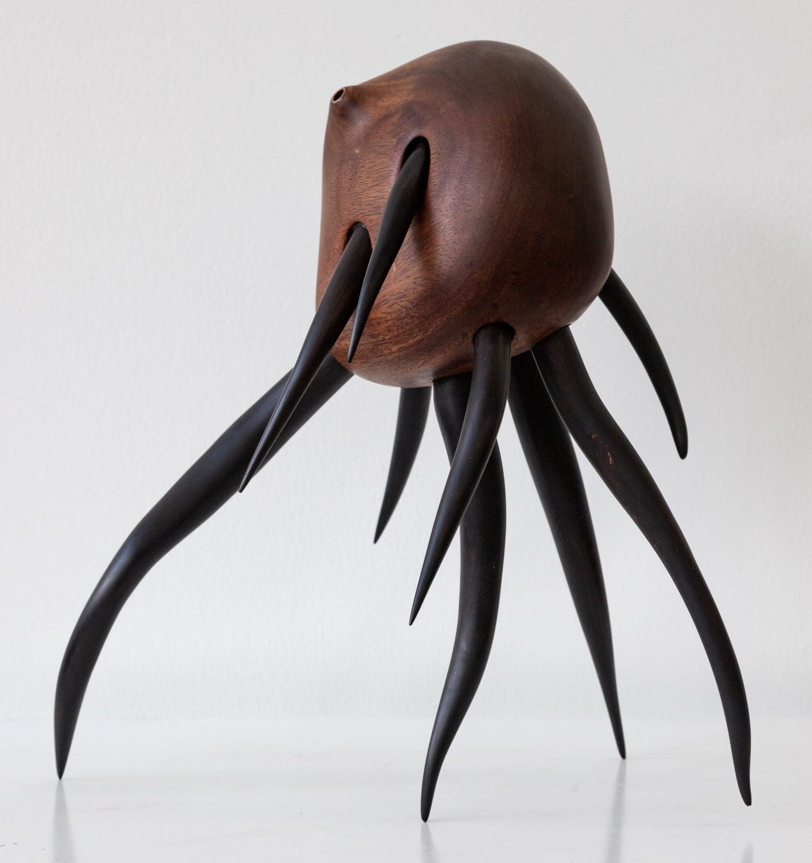 a wooden sculpture by Donald Wasswa with an abstract, sea creature-like form with long tentacles