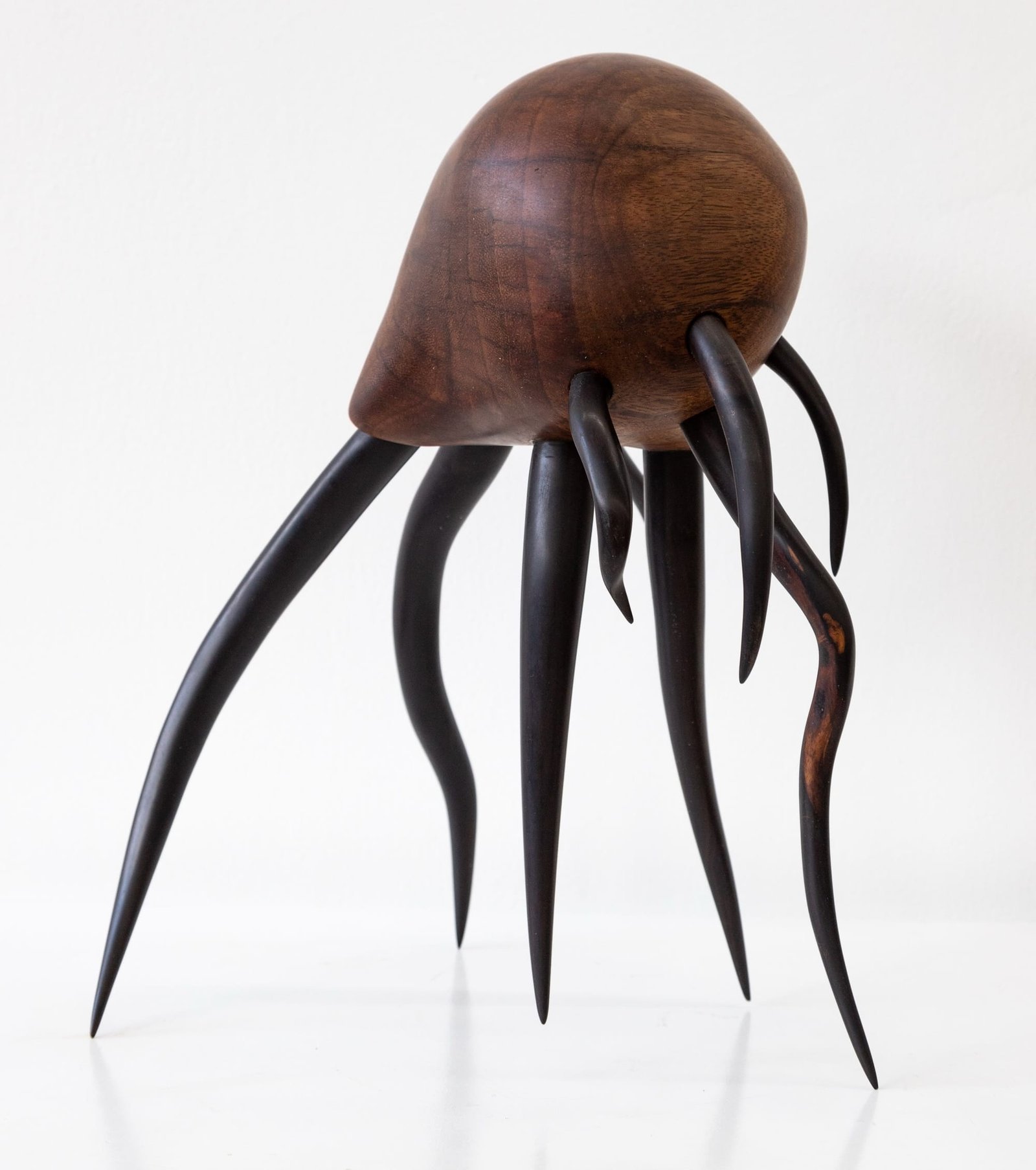 a wooden sculpture by Donald Wasswa with an abstract, sea creature-like form with long tentacles