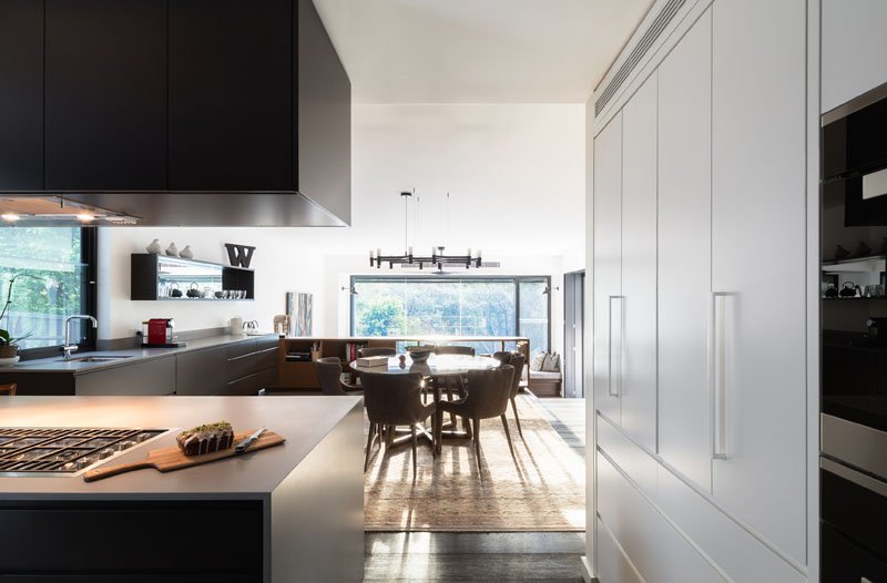 A small bookshelf doubles as a safety barrier above the living room, while the kitchen itself wraps around a corner, opening up sightlines toward the bush.