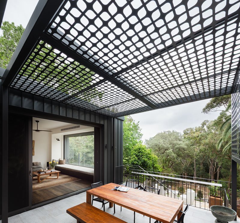 The tiered design makes room for an outdoor dining area that rises out of the backyard. Stone landscaping frames the space, creating a strong connection between the house and the bushland setting.