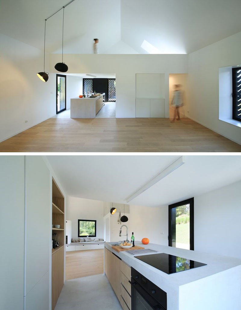 The bright interior is the opposite of the dark exterior. The kitchen island houses both the cooktop and sink, forming the heart of the open-plan space with views in every direction.