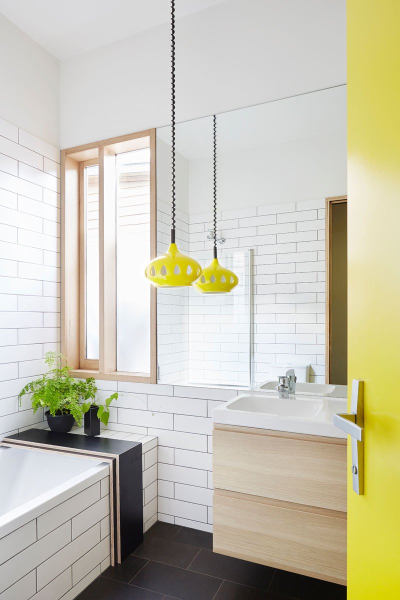 In this bathroom, a bright yellow door and matching pendant light bring a playful energy, standing out against the crisp black-and-white palette of the rest of the room. It’s a small but memorable touch that reflects the family’s personality.