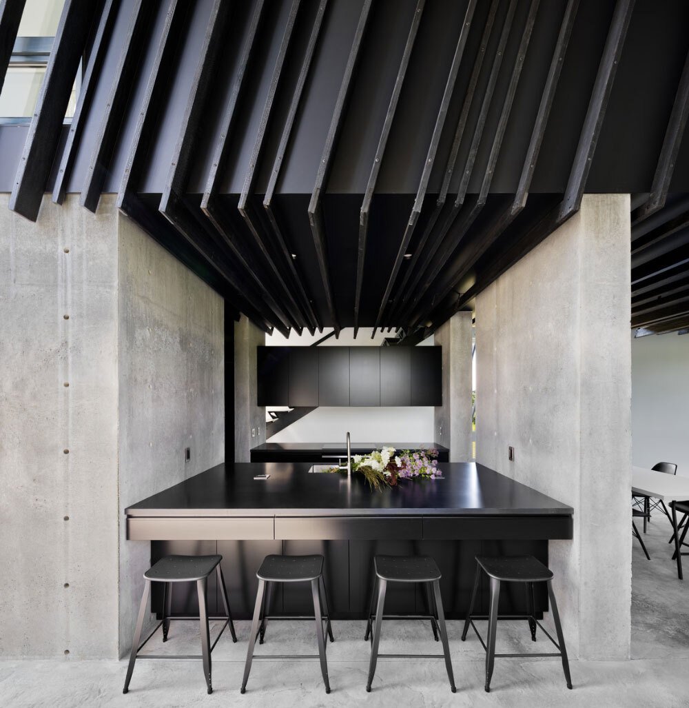 Matte-black cabinetry and a crisp black-and-white dining space define this modern kitchen, sleek, simple, and quietly luxurious.