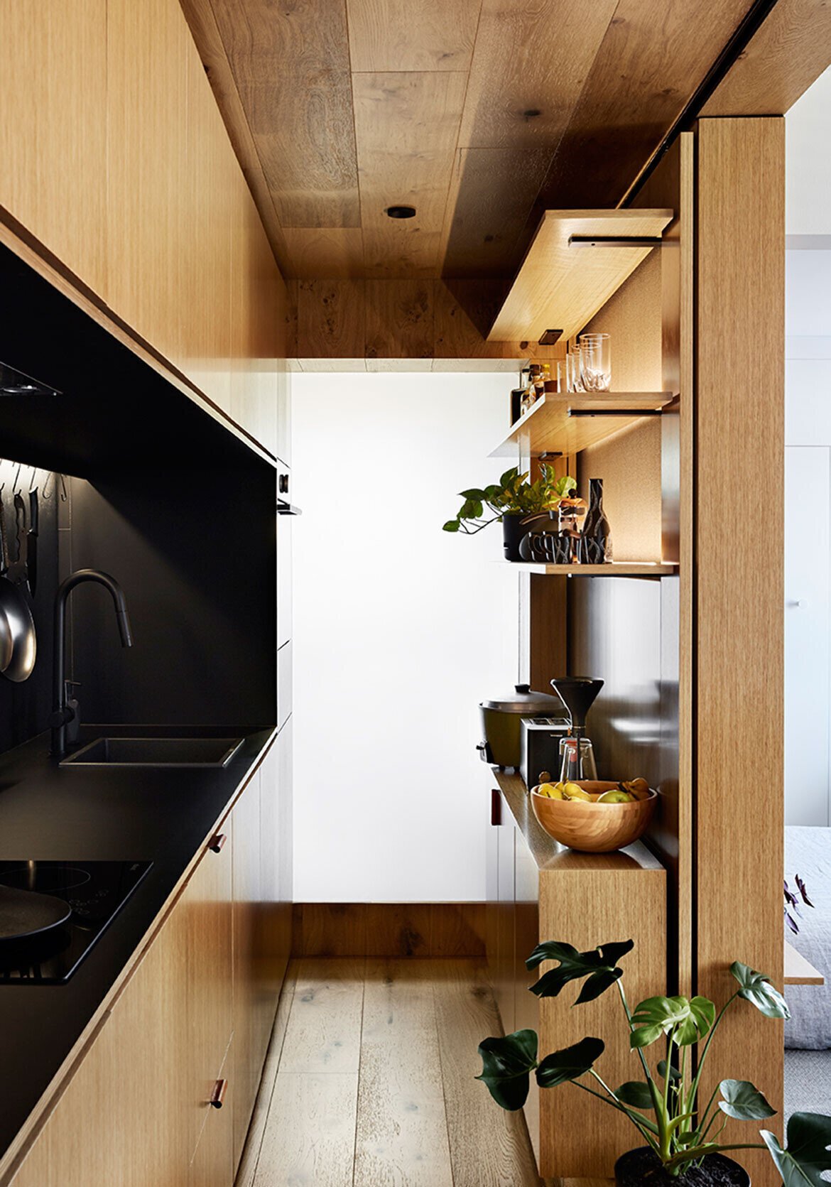 An internal window with switchable privacy film brings borrowed light from the bathroom into the kitchen.